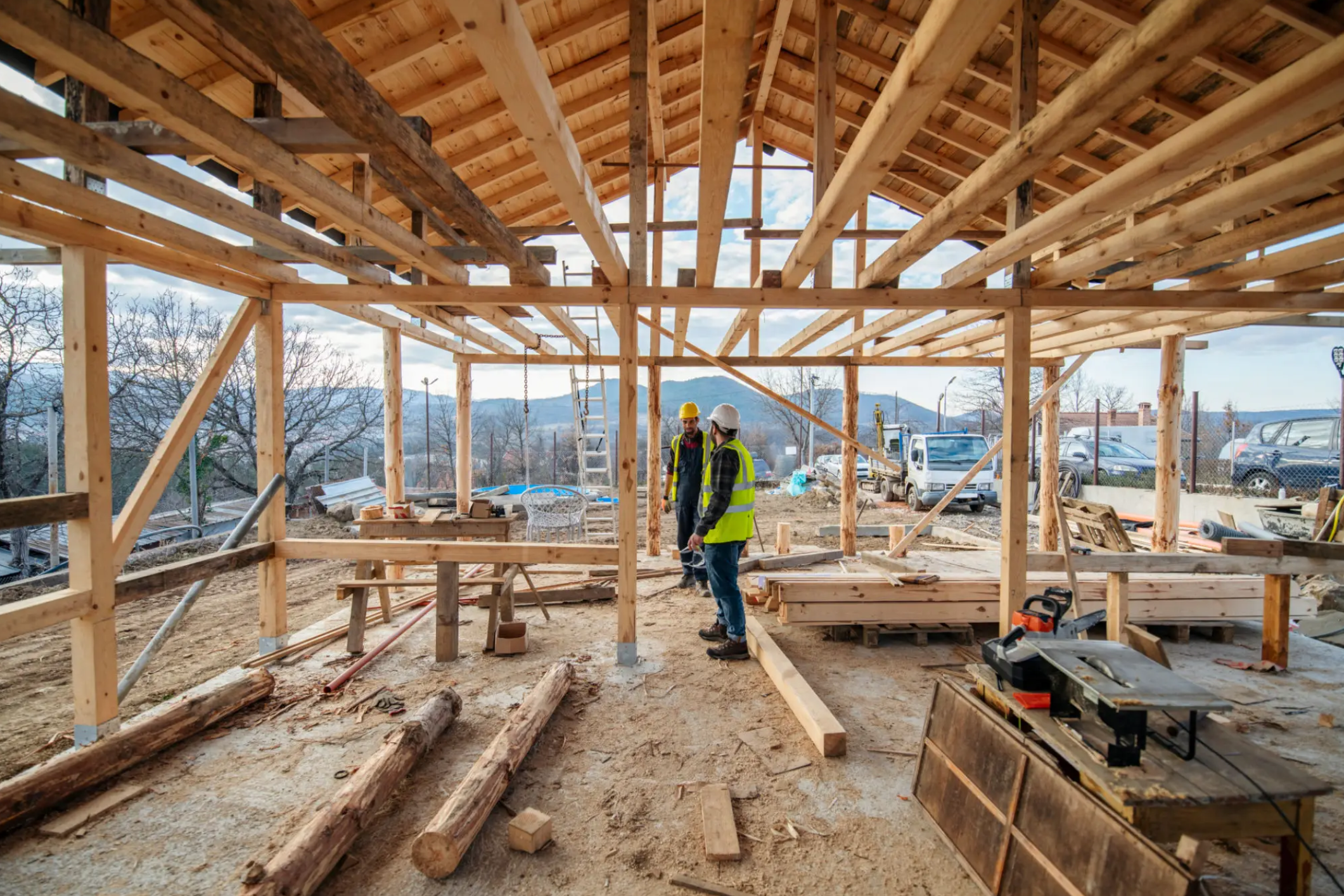 Two construction workers in wooden house framing